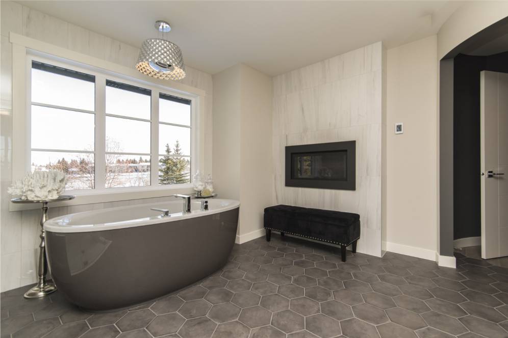 Modern bathroom with a freestanding tub, fireplace, and snow view outside the window
