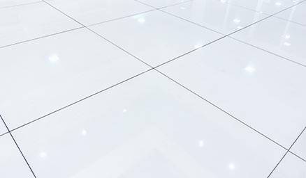 A shiny white tiled floor with reflections of overhead lights