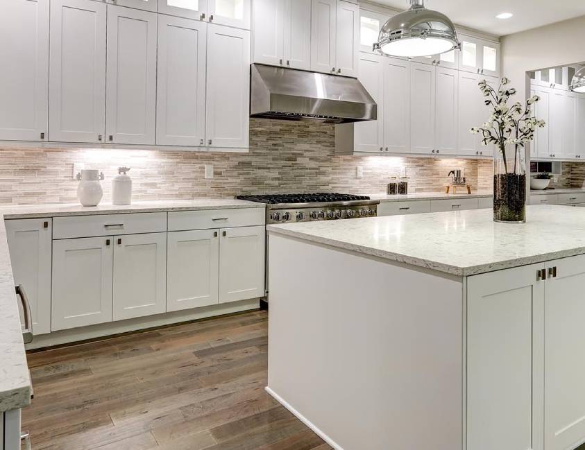 Modern kitchen interior with white cabinetry, marble countertops, and stainless steel appliances