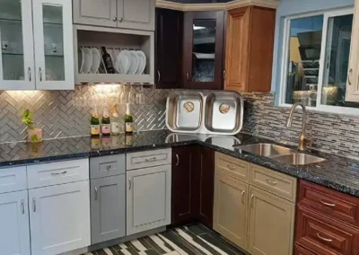 A modern kitchen with mixed cabinet colors, herringbone backsplash, and striped floor