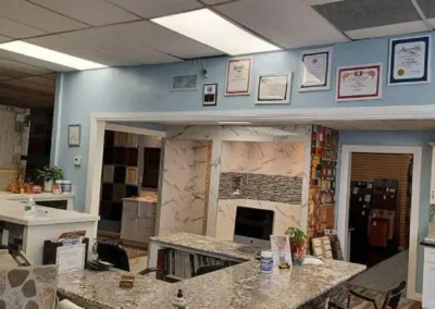 Interior of a room with stone bar counter, fireplace, certificates on the wall, and a white cabinet