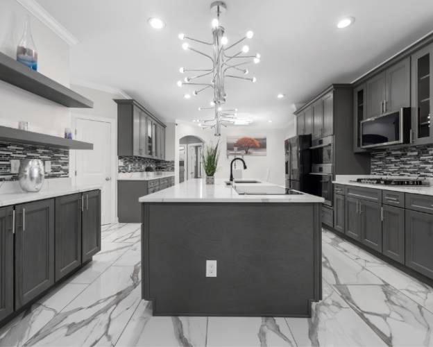 Modern kitchen interior with dark cabinets, white countertops, and stylish light fixture